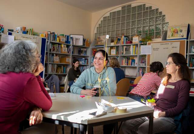 Drei Personen sitzen an einem Tisch und unterhalten sich.